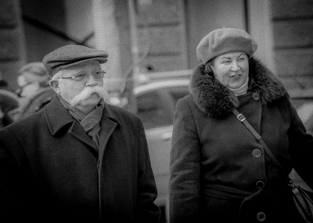 Blurred close-up of two older pedestrians in winter clothes